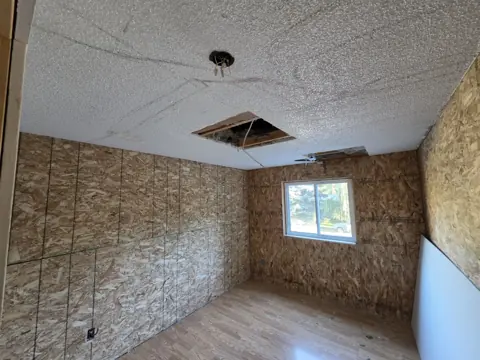 Bedroom with plywood walls and an existing textured ceiling