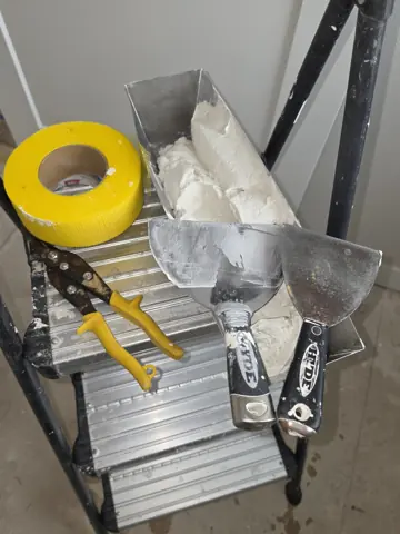 Dan’s mud pan, taping knives, and mesh tape on a work platform